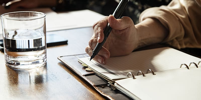 A person writing on paper with a pen.